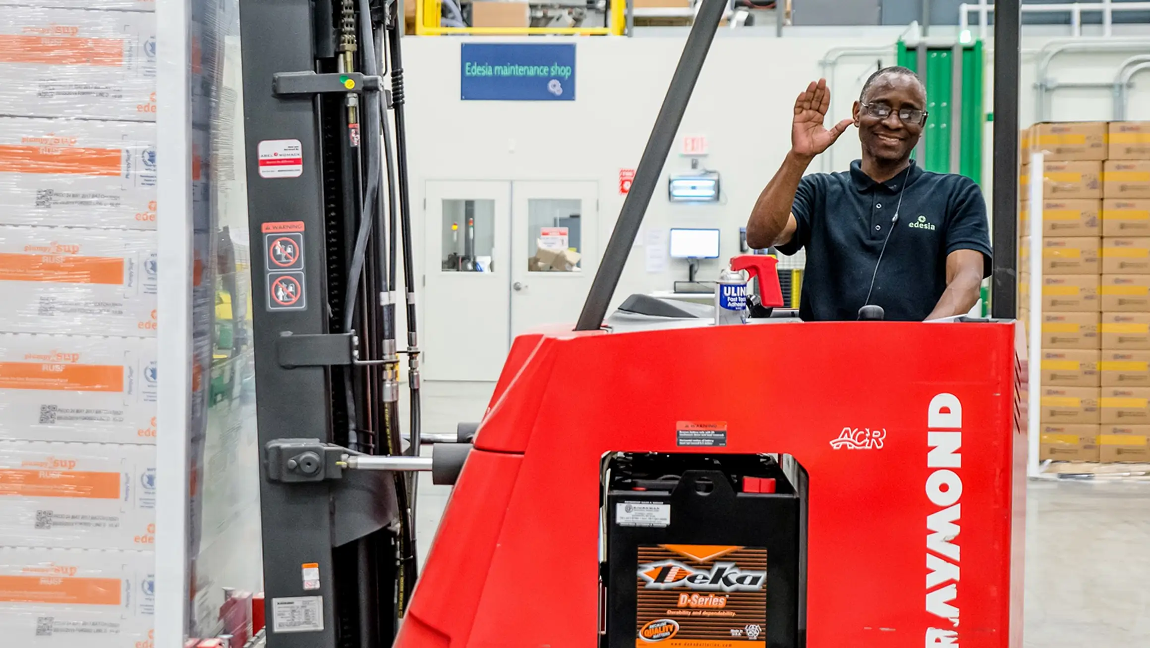 Employee waving from a forklift